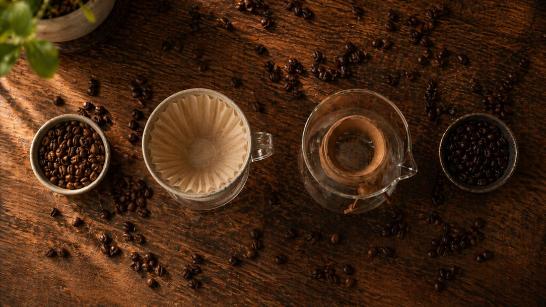 Top-down pour-over coffee setup with dripper, glass carafe, whole beans, and warm moody lighting on a dark wooden table